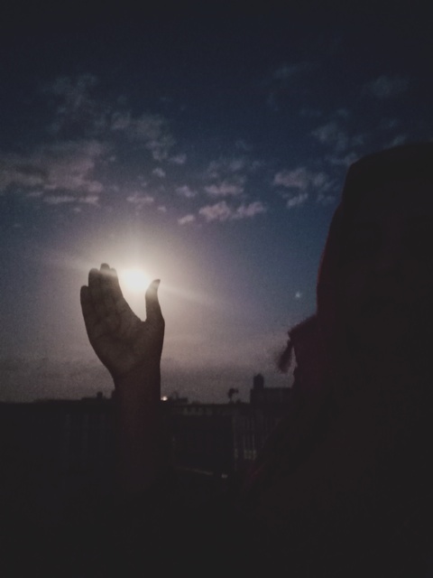 A girl watching full moon and catching with her hands