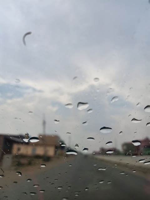 Raindrops on windscreen of car on a road