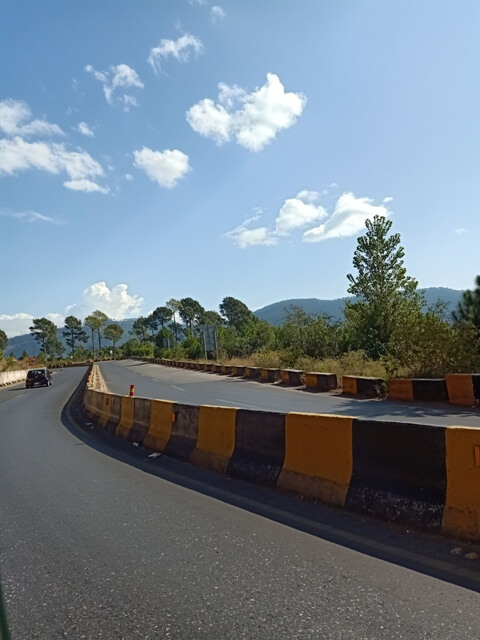 A hill station road with blue sky and clouds