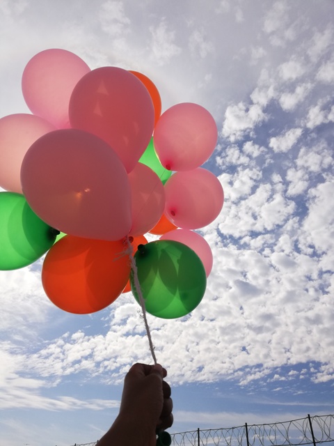 Colorful balloons in hand with sky in the background