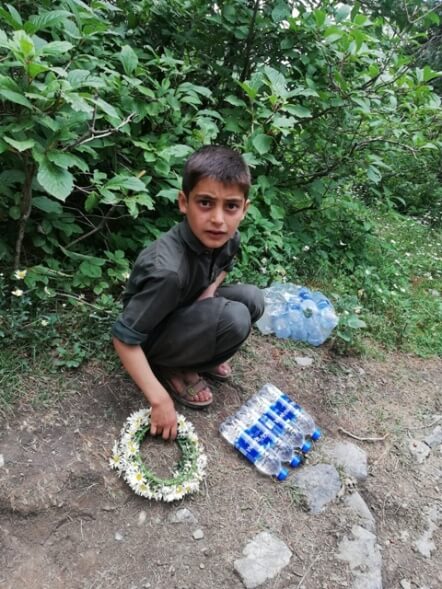A small boy selling flowers and water on the hiking way