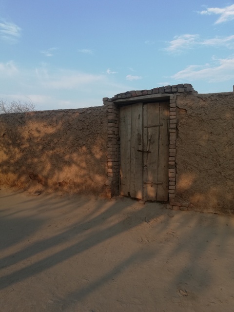 A closed wooden door in a mud wall
