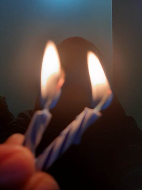 Two candles burning with a girl in background 