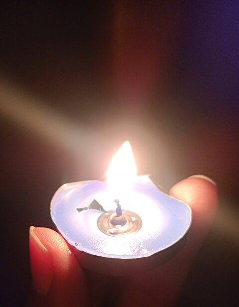 Tiny round candle burning in hand 